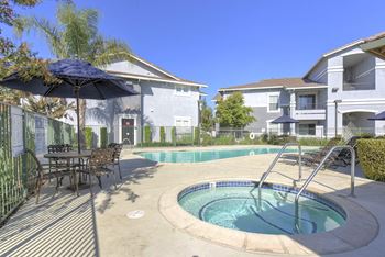 A pool with a hot tub and a table with chairs.